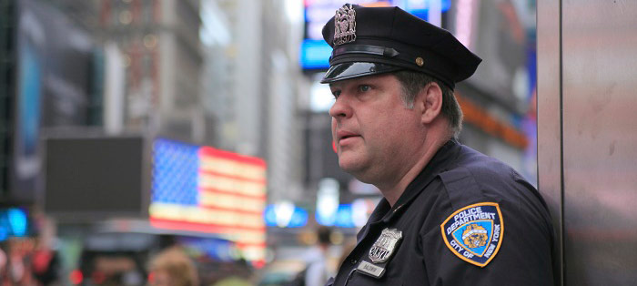 An NYPD police officer appears concerned while standing on the city streets.