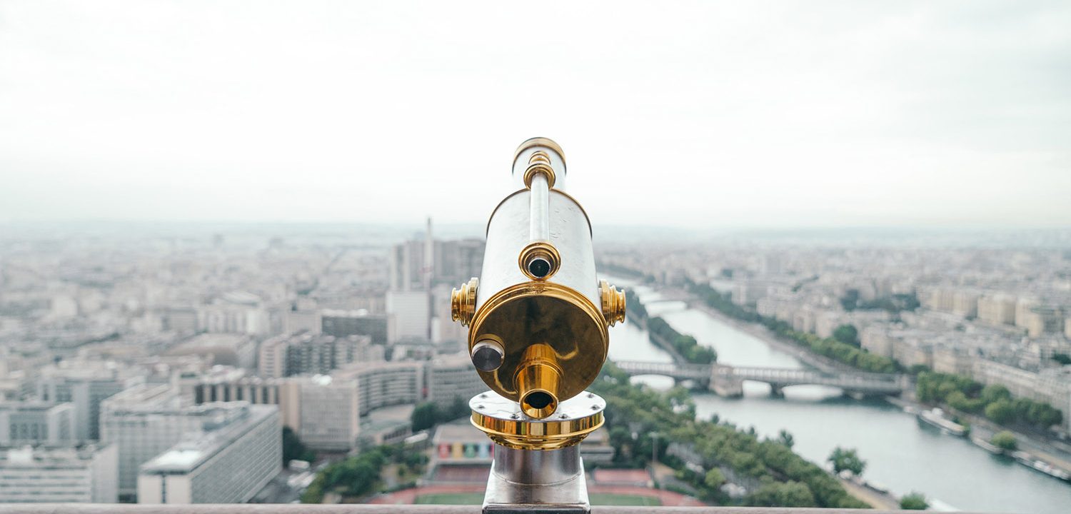 A beautifully gilded telescope overlooks a large city and riverway.