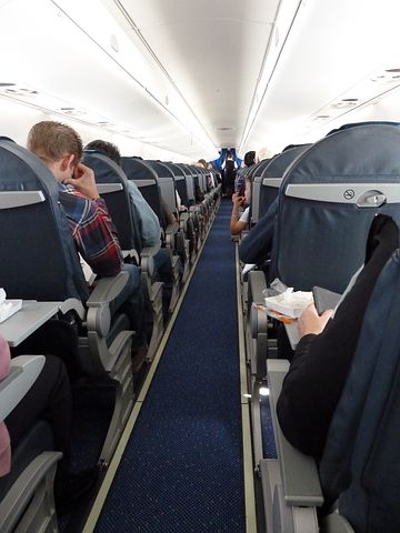A clear aisle down a passenger airplane with passengers seated on either side.