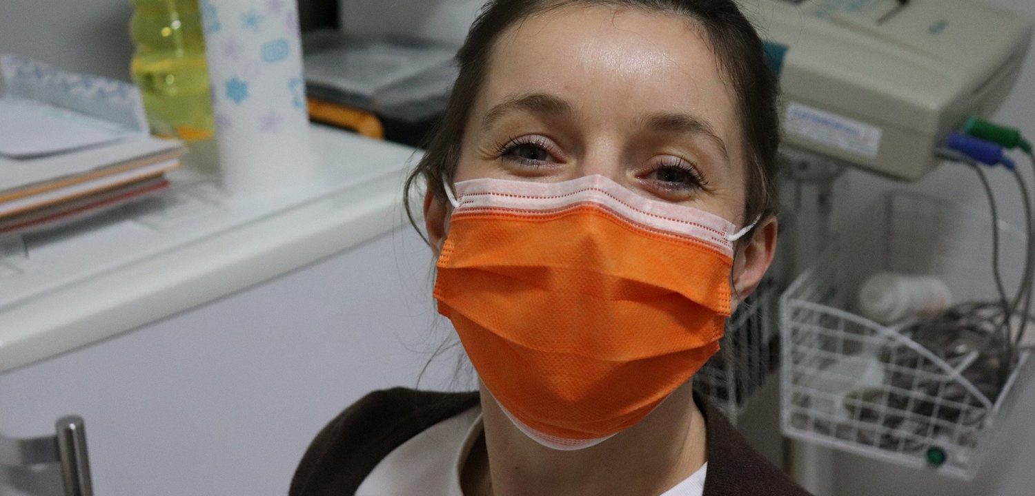 A nurse wearing an orange mask smiles for the camera with her eyes.