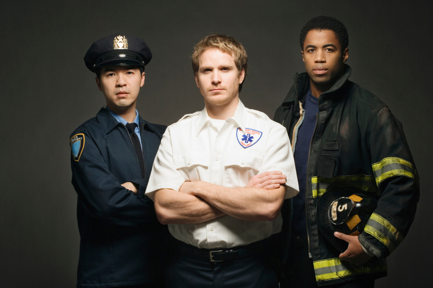 A police officer, paramedic, and firefighter all pose for the camera.