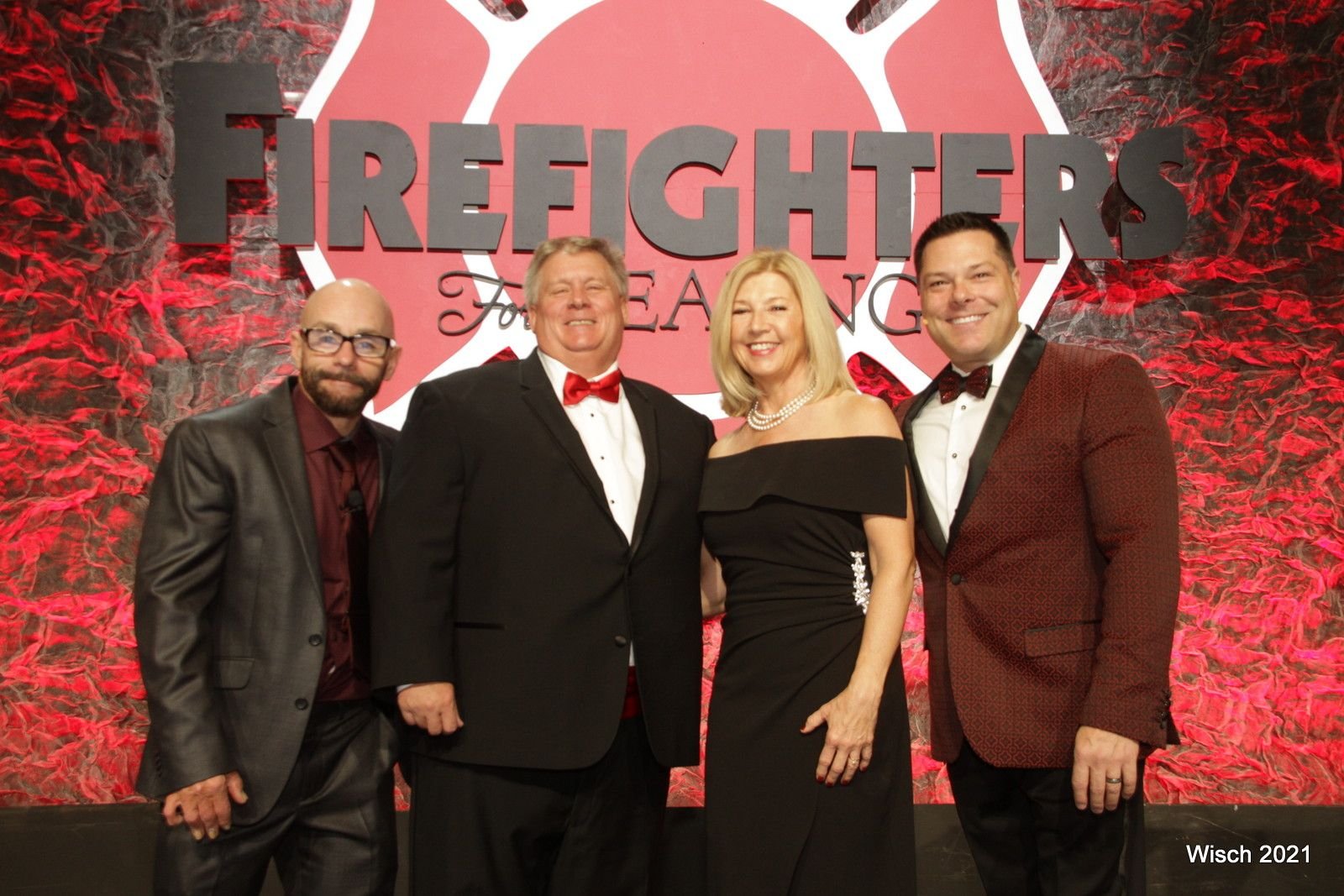 Ron Meuser Jr. poses with three others, smiling for the camera.