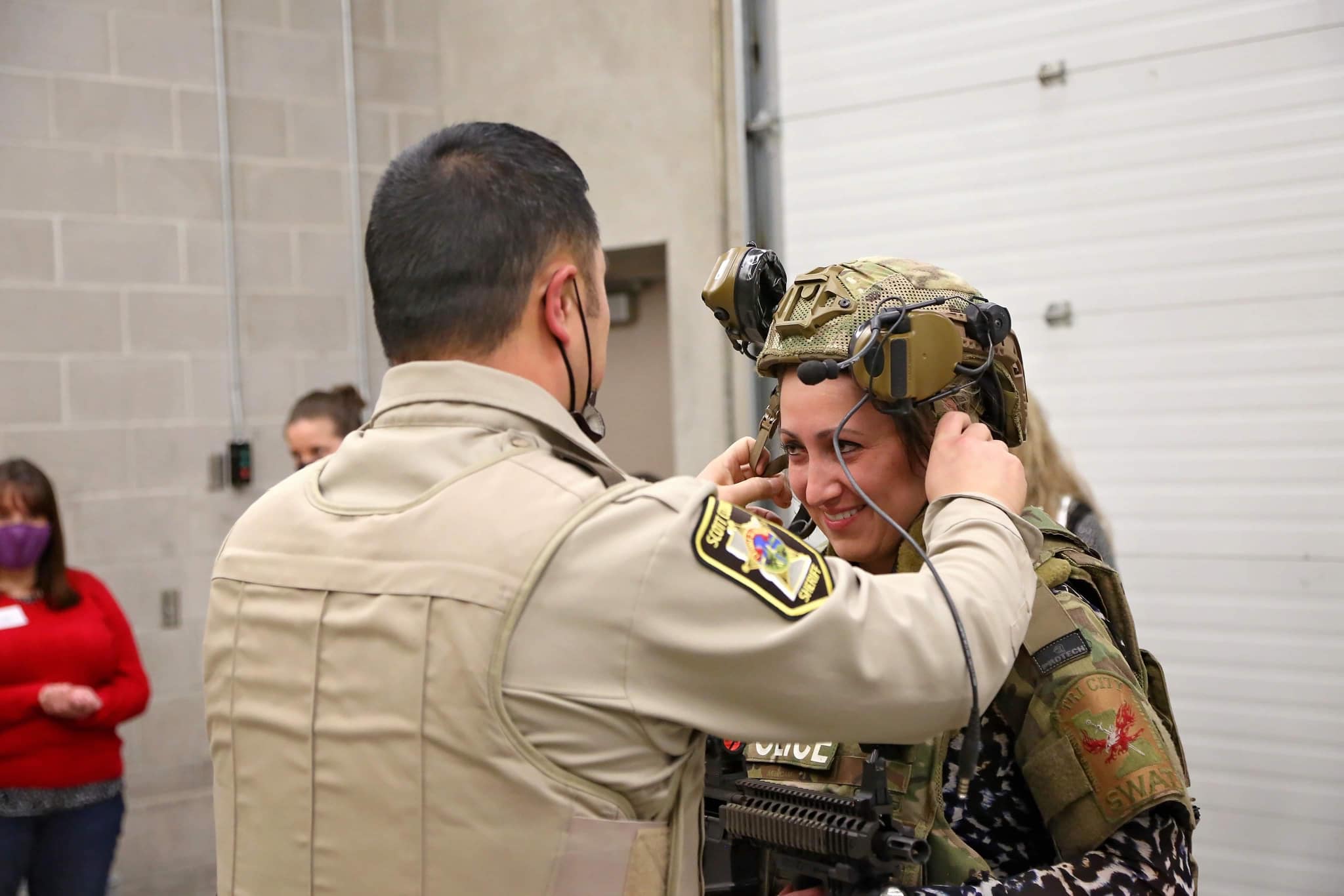An officer assists a woman with her helmet during a community training academy.