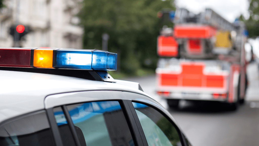 An Actively Lit Police Lightbar on a Patrol Car Parked Behind a Firetruck