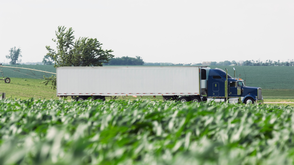 a semi truck driving through a green field
